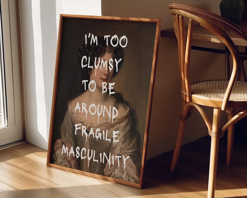 May include: A framed print of a painting of a woman with the text "I'm too clumsy to be around fragile masculinity" superimposed on the image.