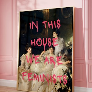May include: A painting of three women in white dresses with the words "In this house we are feminists" written in pink spray paint over the image.