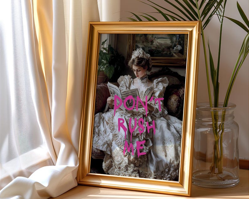 May include: A framed print of a woman in a white dress reading a book. The print has the words "DON'T RUSH ME" written in pink on it.