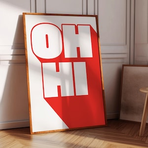 May include: A framed print with the words "OH HI" in bold white letters on a red background. The print is hanging on a white wall.