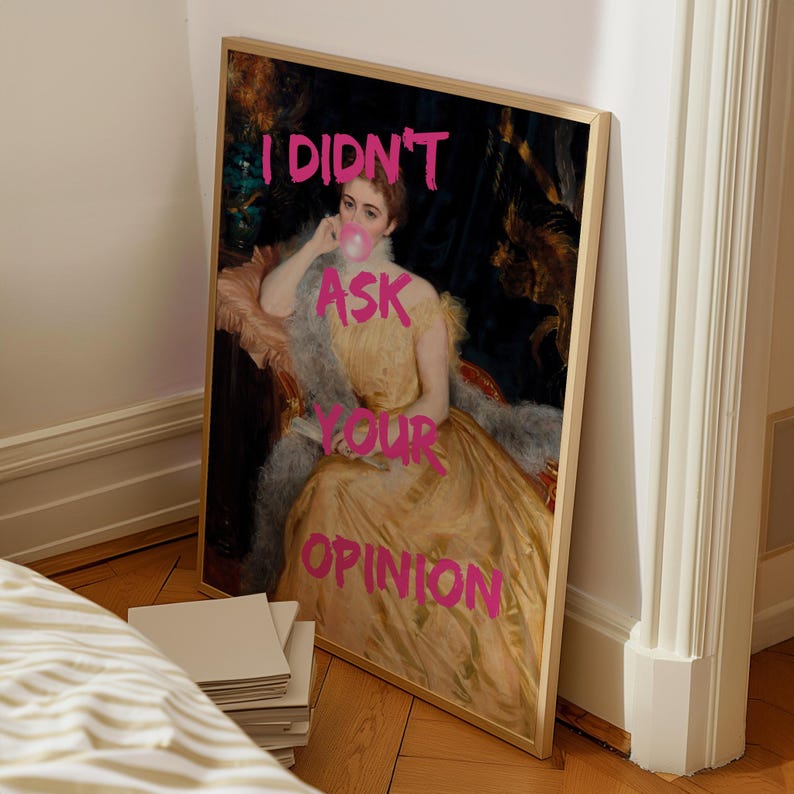 May include: A framed print of a painting of a woman in a yellow dress with the text "I didn't ask your opinion" written in pink.