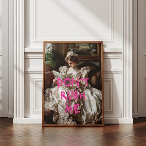 May include: A framed print of a woman in a white dress sitting on a couch and reading a book. The text "DON'T RUSH ME" is written in pink across the image.