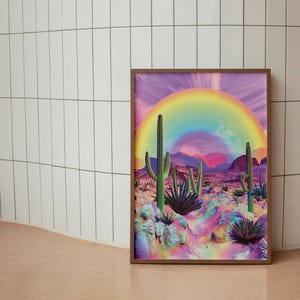 May include: A framed print of a desert landscape with a rainbow arching over the scene. The desert is a vibrant pink and purple with green cacti and plants.