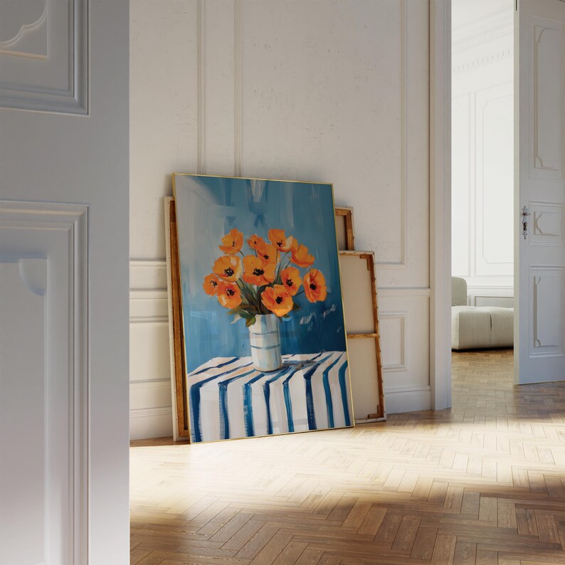 May include: An oil painting depicting orange flowers in a vase with blue and white stripes, set on a table with a blue and white striped cloth. The background is a blue sky. The painting is leaning against a wall.