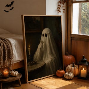 May include: A rectangular framed wall art print featuring a dark, moody painting of a white sheet ghost sitting at a round table. The ghost holds a glass, with a lit candle on the table nearby. The artwork is set in a dimly lit, vintage-style room.
