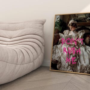 May include: A framed print of a woman in a white dress with the text "DON'T RUSH ME" written in pink on her dress.