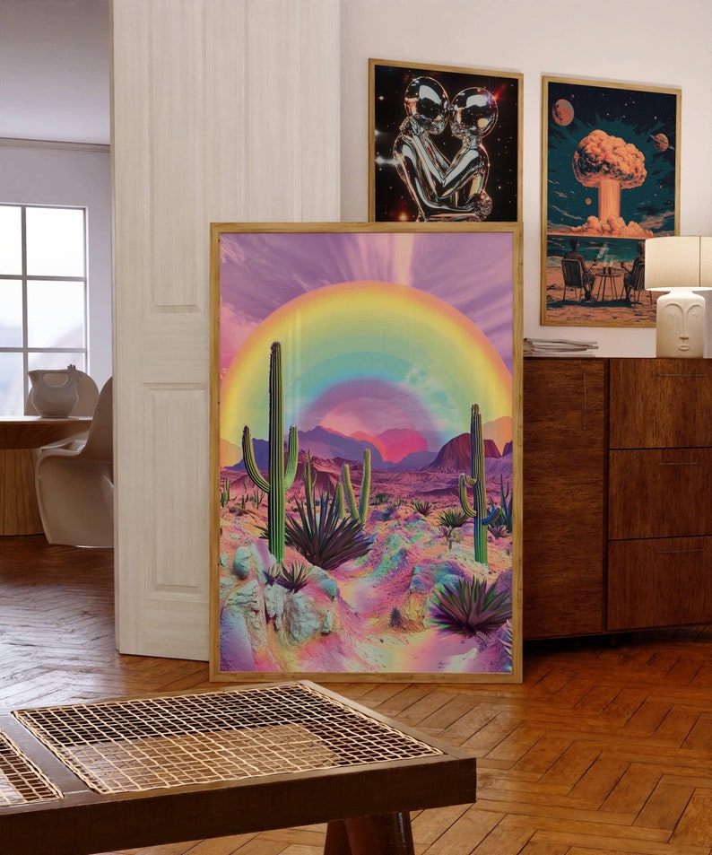 May include: A framed print of a desert landscape with a rainbow arching over the mountains. The desert is a vibrant pink and purple with green cacti and agave plants.
