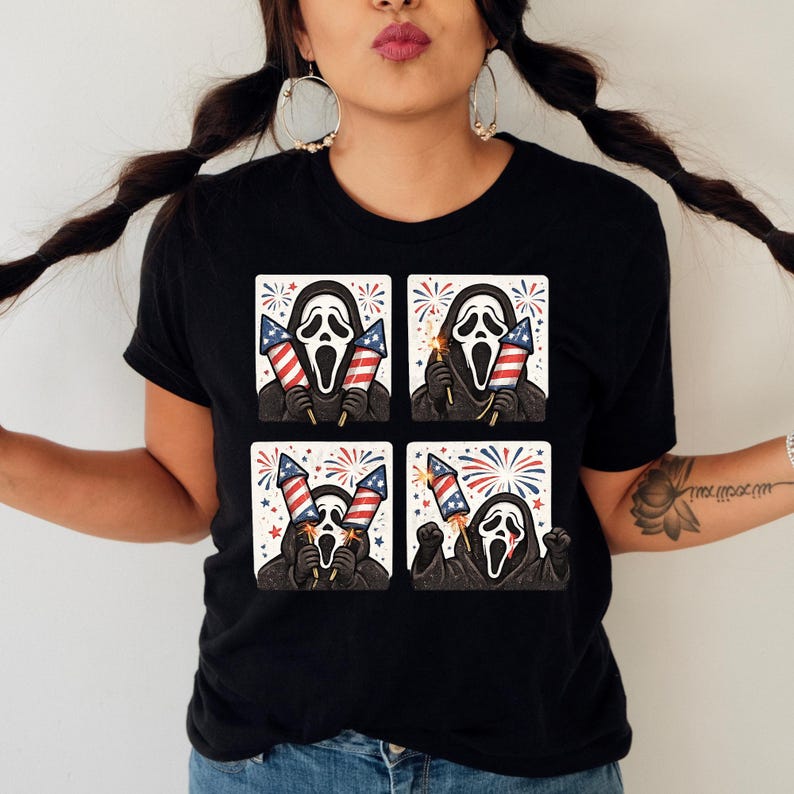 K&ouml;nnte beinhalten: Schwarzes T-Shirt mit einem viergeteilten Grafikdesign der Ghostface-Maske, die Feuerwerk und amerikanische Flaggen h&auml;lt. Das Design verwendet rote, wei&szlig;e und blaue Farben mit einem festlichen Thema.