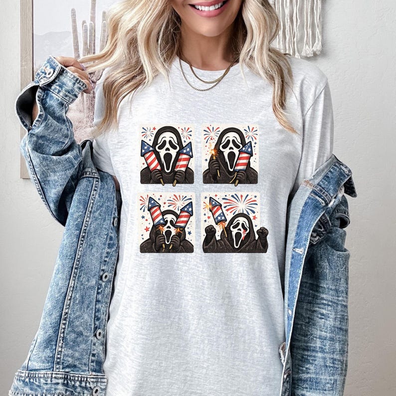 K&ouml;nnte beinhalten: Ein hellgraues Langarmshirt mit einem viergeteilten Design der Ghostface-Maske, die amerikanische Flaggen und Feuerwerk h&auml;lt. Das Design verwendet rote, wei&szlig;e und blaue Farben und feiert den Unabh&auml;ngigkeitstag.