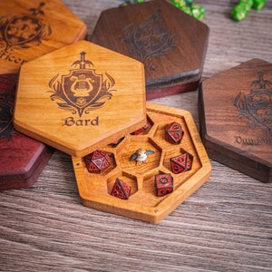 May include: A wooden box with a hinged lid, engraved with the word "Bard" and a lyre design. The box is open, revealing a set of red dice with black markings, and a small figurine of a bird.