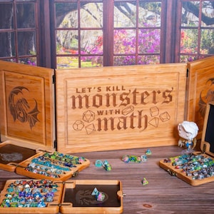 Könnte beinhalten: Holz-Tischspielset mit einem faltbaren Sichtschutz mit der Aufschrift "LET'S KILL monsters WITH math". Enthält Würfelablagen und eine Vielzahl farbiger Würfel. Eine Figur steht rechts vom Bildschirm. Das Set befindet sich auf einer Holzoberfläche.
