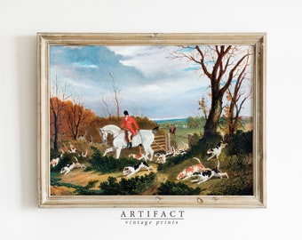 May include: A vintage framed painting depicting a fox hunt scene. A rider on a white horse leads a pack of hounds through a wooded area. The painting is set against a cloudy sky and features a rustic wooden frame.
