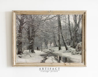 May include: A framed vintage print of a snowy forest scene with a path leading through the trees. The trees are covered in snow and the ground is covered in snow. There is a small stream running through the forest. The print is in a light wood frame.