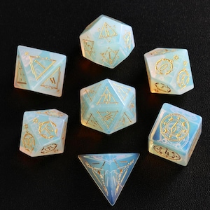 May include: Set of seven iridescent blue and white dice with gold accents and various symbols. The dice are made of a translucent material and have a frosted finish.