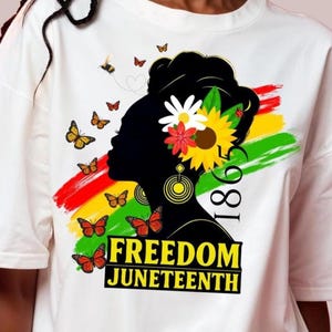 May include: White t-shirt with a black silhouette of a woman's profile decorated with flowers and butterflies. The design includes the text "FREEDOM JUNETEENTH" and the year "1865" with red, yellow, and green brushstrokes.