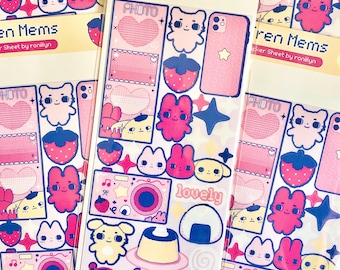 May include: Sheets of stickers with various pink and white designs. The stickers feature cute cartoon characters, hearts, strawberries, cameras, and the text "lovely." The sticker sheets are labeled "Fren Mems" and "Sticker Sheet by roniilyn."