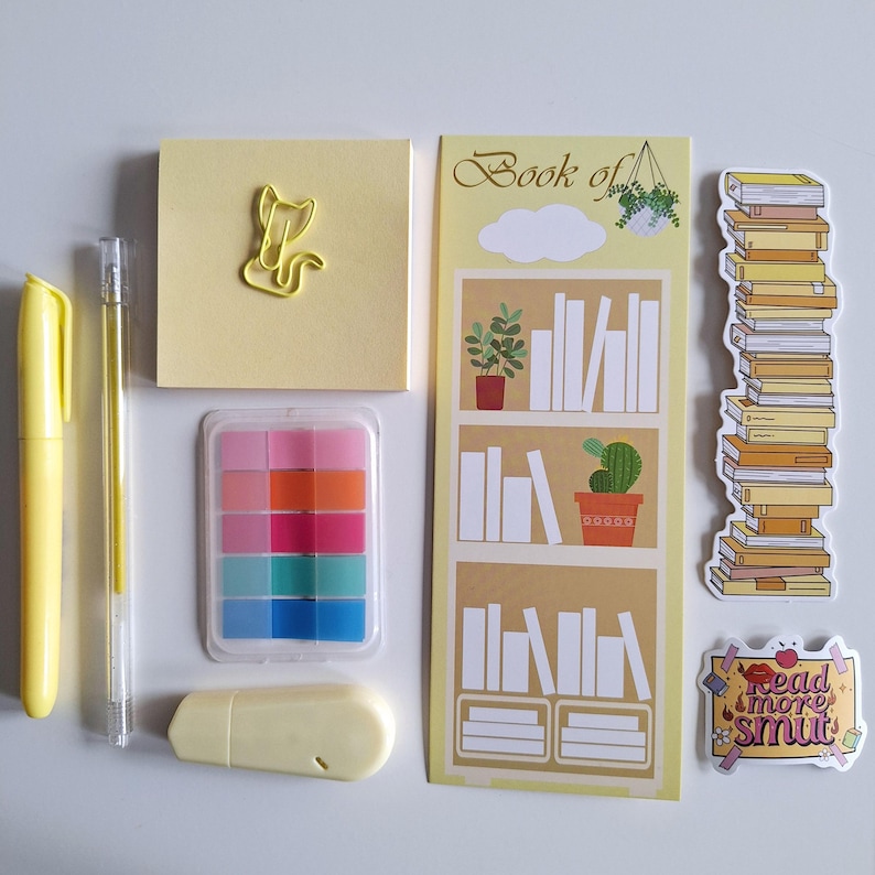 May include: A set of yellow stationery supplies including sticky notes, a pen, a pencil, a paper clip, a small container of colorful sticky notes, a yellow eraser, and a bookmark with a bookshelf design and the text "Book of".