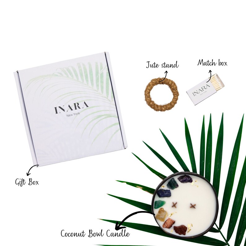 May include: A coconut bowl candle with a white wax and colorful crystals embedded in the wax. The candle is on a green palm leaf. The image also shows a gift box, a jute stand, and a matchbox with matches.