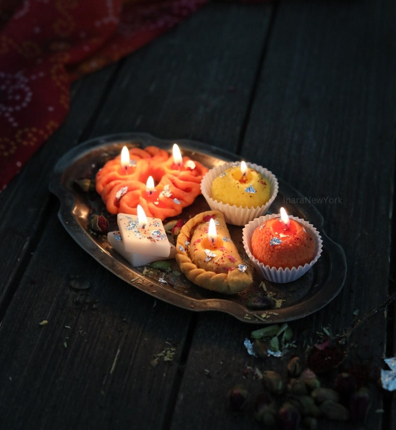 A tray with five lit dessert shaped candles on it