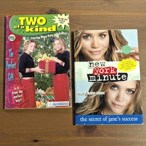 May include: Two paperback books featuring Mary-Kate and Ashley Olsen. The left book is titled Two of a Kind #26 The Perfect Gift, showing the pair with a gift. The right book is titled New York Minute, featuring close-up portraits of the twins.