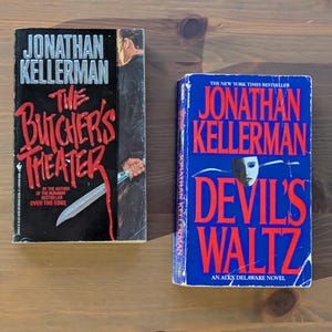 May include: Two paperback books by Jonathan Kellerman. The book on the left is titled "The Butcher's Theater" with red and white text on a black background. The book on the right is titled "Devil's Waltz" with red text on a blue background.