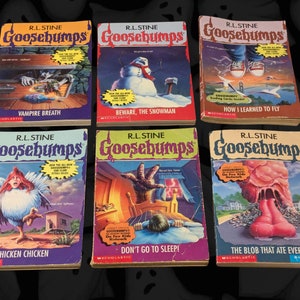 以下が含まれることがあります： R.L. Stineによる6冊のヴィンテージGoosebumps本が展示されており、それぞれにユニークな表紙イラストが描かれています。「Vampire Breath」、「Beware, the Snowman」、「How I Learned to Fly」などのタイトルがあります。本は鮮やかな色とGoosebumpsのロゴが特徴です。