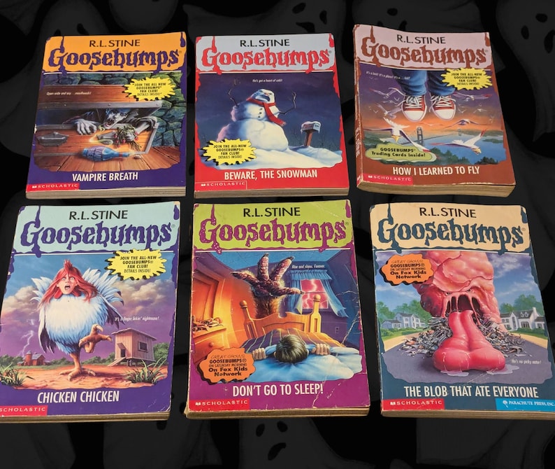 以下が含まれることがあります： R.L. Stineによる6冊のヴィンテージGoosebumps本が展示されており、それぞれにユニークな表紙イラストが描かれています。「Vampire Breath」、「Beware, the Snowman」、「How I Learned to Fly」などのタイトルがあります。本は鮮やかな色とGoosebumpsのロゴが特徴です。