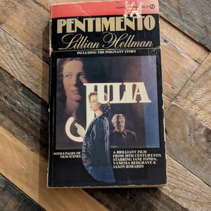Puede incluir: Libro de bolsillo vintage titulado "Pentimento" de Lillian Hellman, con la película "Julia". La portada tiene una parte superior roja con el título en letras negras. La portada incluye imágenes de las estrellas de la película, Jane Fonda, Vanessa Redgrave y Jason Robards.