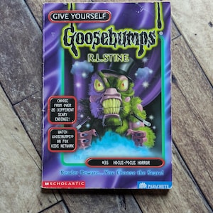 May include: A Give Yourself Goosebumps book titled Hocus-Pocus Horror by R.L. Stine, featuring a green, furry creature in a top hat on a purple background. The cover includes text about 20 scary endings and the Fox Kids Network broadcast.