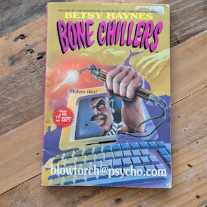 Può includere: Un libro tascabile vintage intitolato "Bone Chillers" di Betsy Haynes. La copertina presenta un'illustrazione minacciosa di una persona con un cannello, un computer e la scritta "Delete this!". Il libro era una serie TV su ABC.