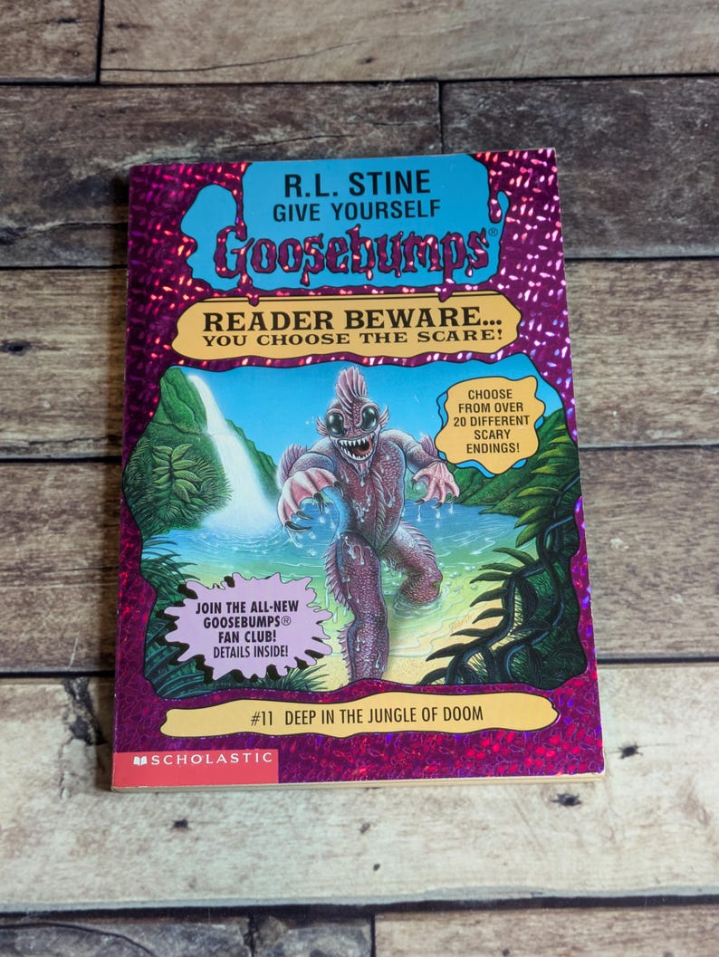 May include: A Give Yourself Goosebumps book titled Deep in the Jungle of Doom by R.L. Stine. The cover features a purple holographic border, a central illustration of a swamp creature in a jungle setting, and text promoting a fan club.