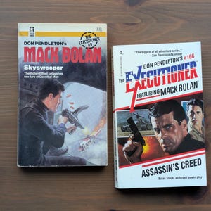 May include: Two mass market paperback books from The Executioner series by Don Pendleton. The left book is titled Skysweeper, featuring an illustration of a man firing a weapon. The right book is titled Assassin's Creed, featuring a portrait of a man.