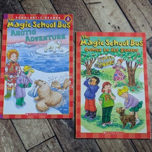 Könnte beinhalten: Zwei Kinderbücher, "The Magic School Bus Arctic Adventure" und "The Magic School Bus Comes to Its Senses". Das erste Buch zeigt einen Eisbären und ein Walross. Das zweite Buch zeigt Kinder in der Nähe eines gelben Schulbusses. Beide Bücher haben rot-orange Ränder.