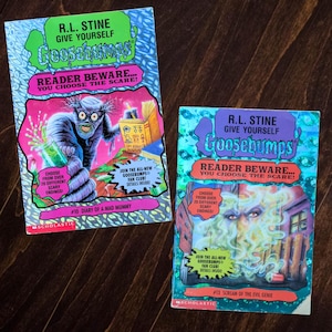 May include: Two R.L. Stine Give Yourself Goosebumps books. The left book is #10 Diary of a Mad Mummy with a mummy illustration. The right book is #13 Scream of the Evil Genie featuring a green smoke illustration. Both have Scholastic logos.