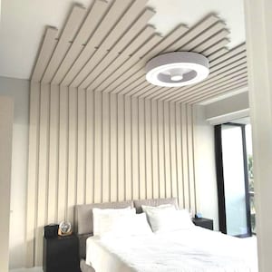 May include: A white bed with a white headboard and white bedding. The headboard is made of vertical wood panels. The ceiling has a white ceiling fan and a wood slat ceiling.