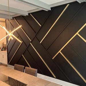 Könnte beinhalten: Eine schwarze Wand mit einem geometrischen Muster aus goldenen Linien. Die Wand besteht aus Holzpaneelen und hat ein modernes Design.