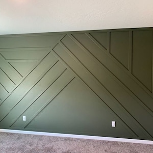 May include: A wall with a geometric pattern made of dark green painted wood panels. The panels are arranged in a series of intersecting lines and triangles.