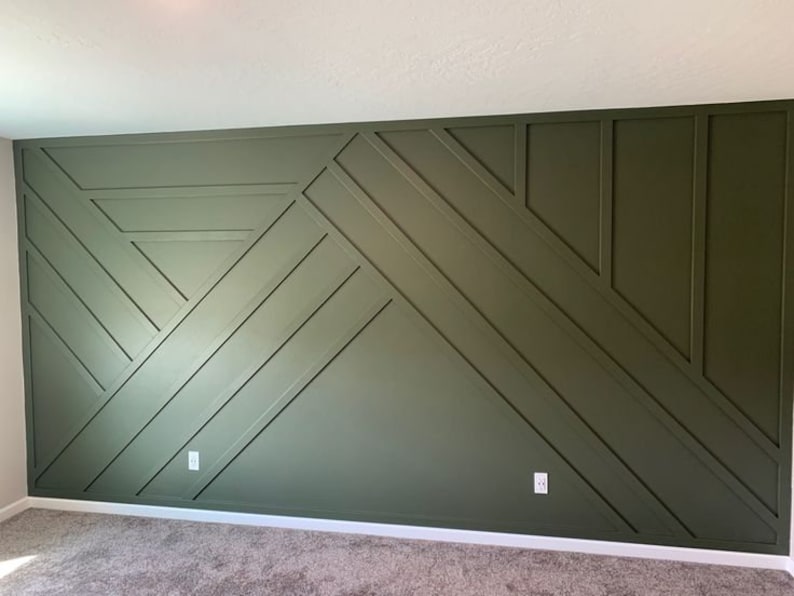 May include: A wall with a geometric pattern made of dark green painted wood panels. The panels are arranged in a series of intersecting lines and triangles.