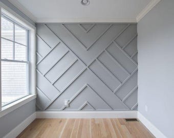 May include: A room with a grey accent wall featuring a geometric pattern. The wall is painted a light grey and the pattern is made up of white squares and rectangles. The room has white trim and a large window with white blinds. The floor is made of light wood.