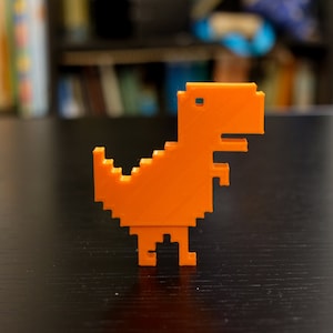 May include: Orange 3D printed dinosaur figurine in a pixelated style. The dinosaur is standing on a black surface.