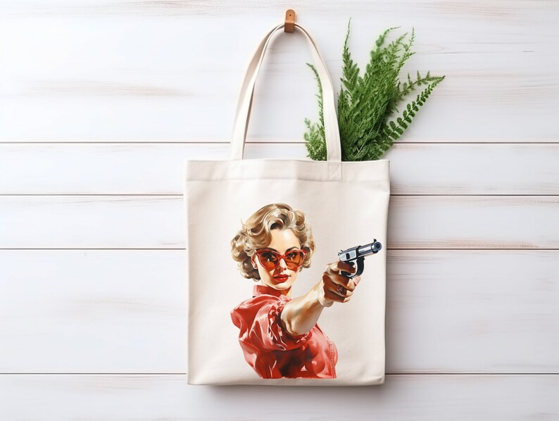May include: A white tote bag with a red and white illustration of a woman wearing red sunglasses and holding a gun. The woman has blonde hair and is looking directly at the viewer.