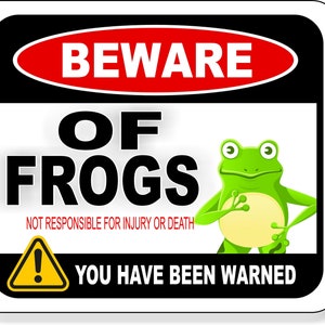 May include: A white sign with black and red borders. The sign reads "Beware of Frogs" in black bold letters. A cartoon green frog with a yellow belly is pictured on the sign. The sign also reads "Not responsible for injury or death" in red letters. A yellow triangle with an exclamation point is below the frog. The sign ends with the text "You have been warned" in black letters.