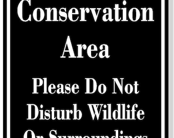 May include: Black and white sign with rounded top corners that reads "Conservation Area Please Do Not Disturb Wildlife Or Surroundings".