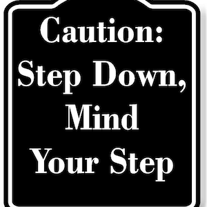 May include: Black and white sign with rounded corners and a white border. The sign reads "Caution: Step Down, Mind Your Step".