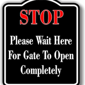 May include: Black and white sign with a red "STOP" sign. The sign reads "Please Wait Here For Gate To Open Completely."