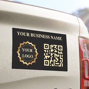 May include: Black rectangular business magnet with gold text and logo. The magnet features the text "YOUR BUSINESS NAME", a QR code, and a gold logo design that says "YOUR LOGO". The magnet is attached to the back of a white vehicle.