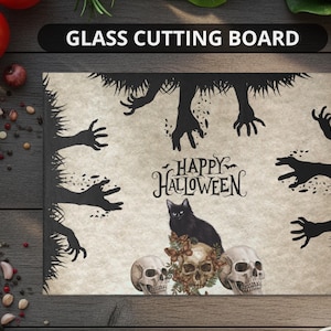 May include: Rectangular glass cutting board with a Halloween theme. The design features black silhouettes of hands, a black cat, skulls, and the text "HAPPY HALLOWEEN". The background is a light beige color.