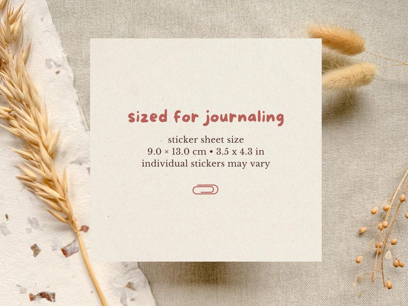 Sticker sheet shown next to a journal and pen to demonstrate scale, indicating the size of the sticker sheet and how it fits common journaling notebooks.