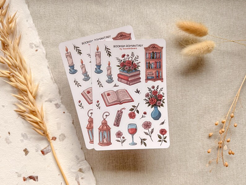 Bookish Romantasy cottagecore sticker sheet featuring pile of books with flowers, open book, lantern, vase with flowers, shelf full of books, single floral stickers, and glass of wine, with dreamy book lover aesthetic.