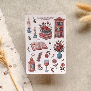 Bookish Romantasy cottagecore sticker sheet featuring pile of books with flowers, open book, lantern, vase with flowers, shelf full of books, single floral stickers, and glass of wine, with dreamy book lover aesthetic.